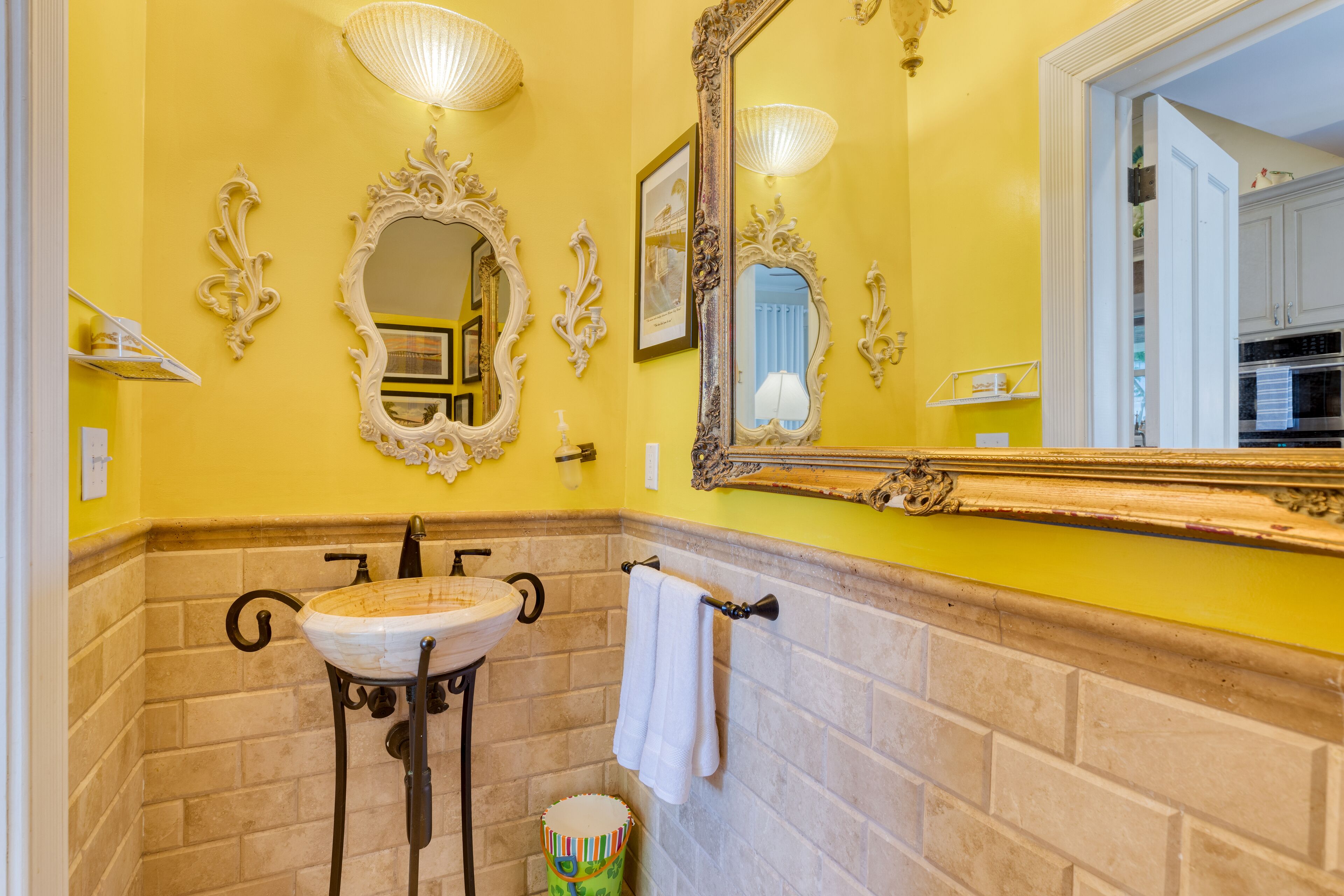 Un baño con una pared amarilla, un lavamanos blanco y un espejo grande.