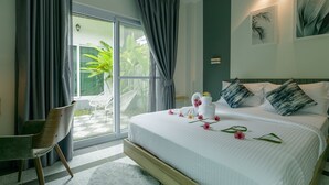 Une chambre d’hôtel avec un grand lit, une chaise, une vue sur la verdure et des œuvres d’art accrochées au mur.