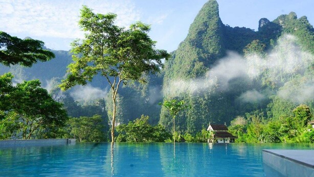 Une piscine aux eaux cristallines, offrant une vue sur une végétation luxuriante et une montagne en arrière-plan.