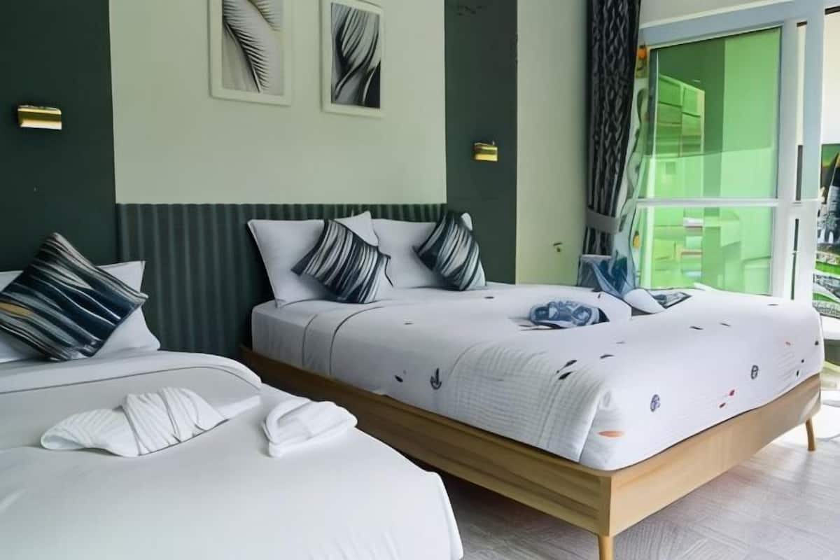 A hotel room with two beds, a large window, and a view of the outside.