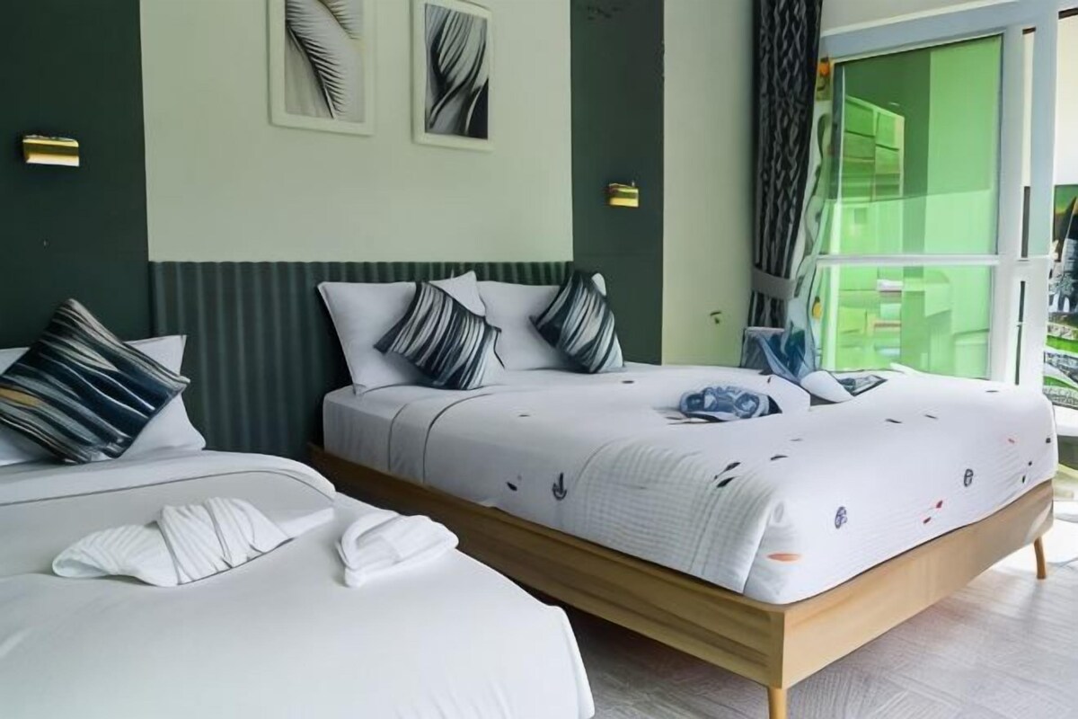 A hotel room with two beds, a large window, and a view of the outside.