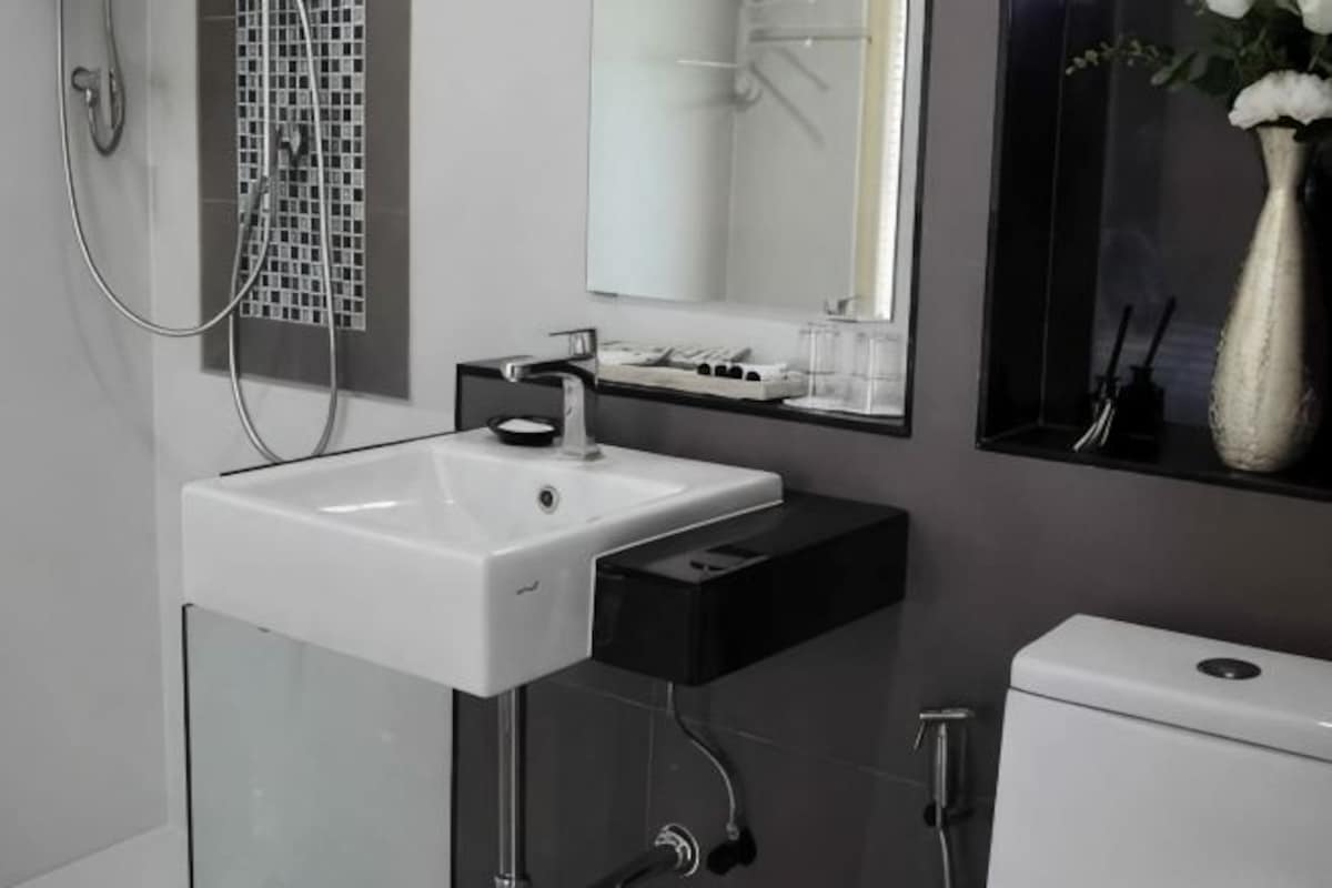 A modern bathroom with a white sink, black countertop, and a toilet.