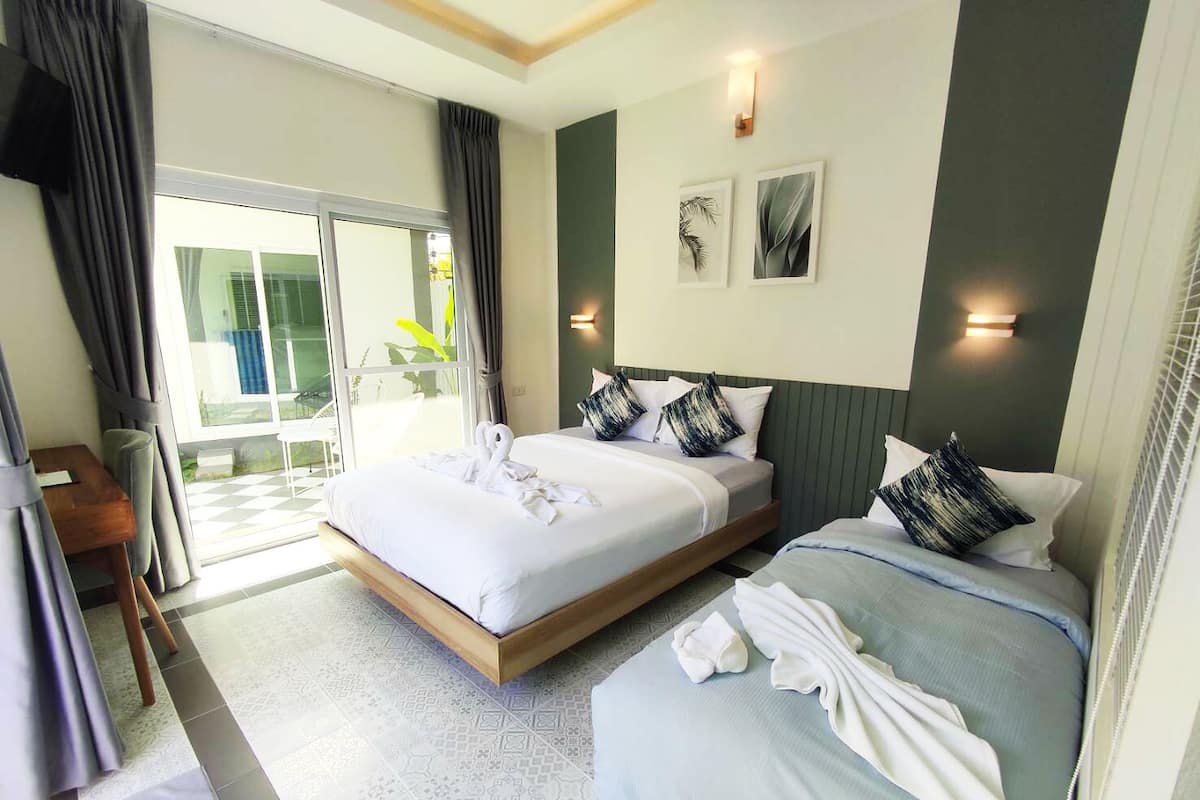 A hotel room with a large bed, a smaller bed, a desk, and a view of the outdoors.
