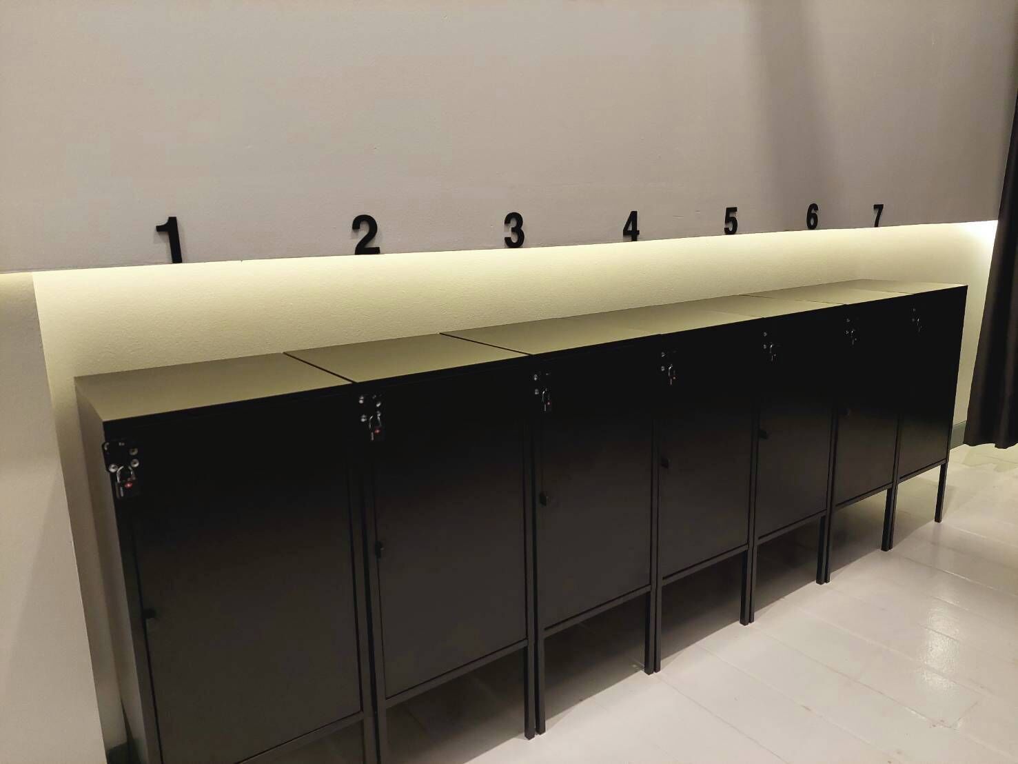 A row of black lockers with a white counter and numbered labels from 1 to 7.