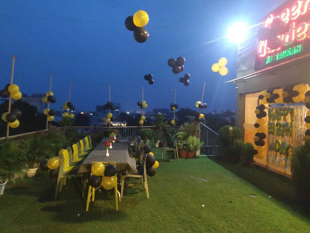 An outdoor dining area with a long table and chairs, decorated with balloons.