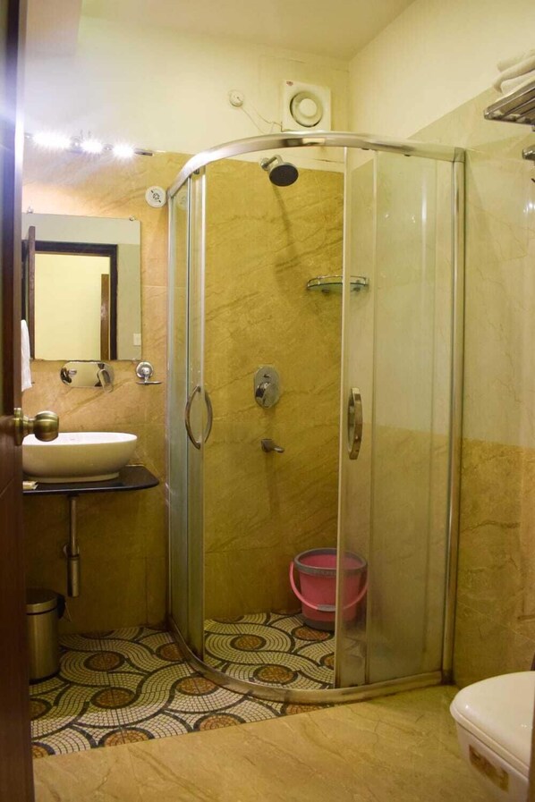 A bathroom with a glass-enclosed shower, a sink, and a toilet.