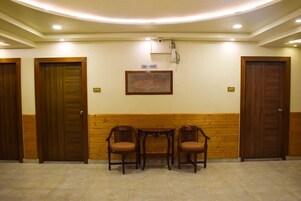 A reception area with wooden paneling, a tiled floor, and three wooden chairs.