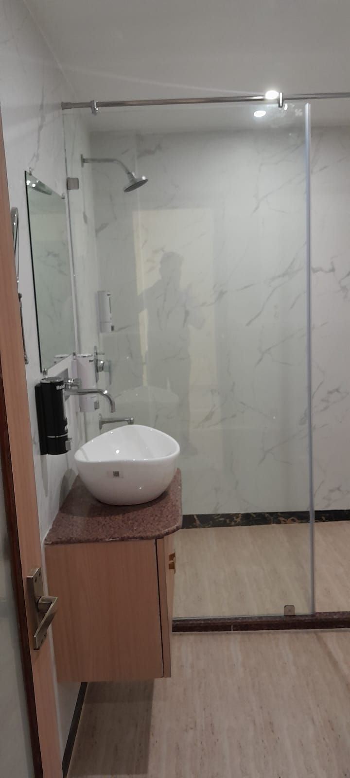 A bathroom with a white sink, a glass shower enclosure, and a wooden cabinet.