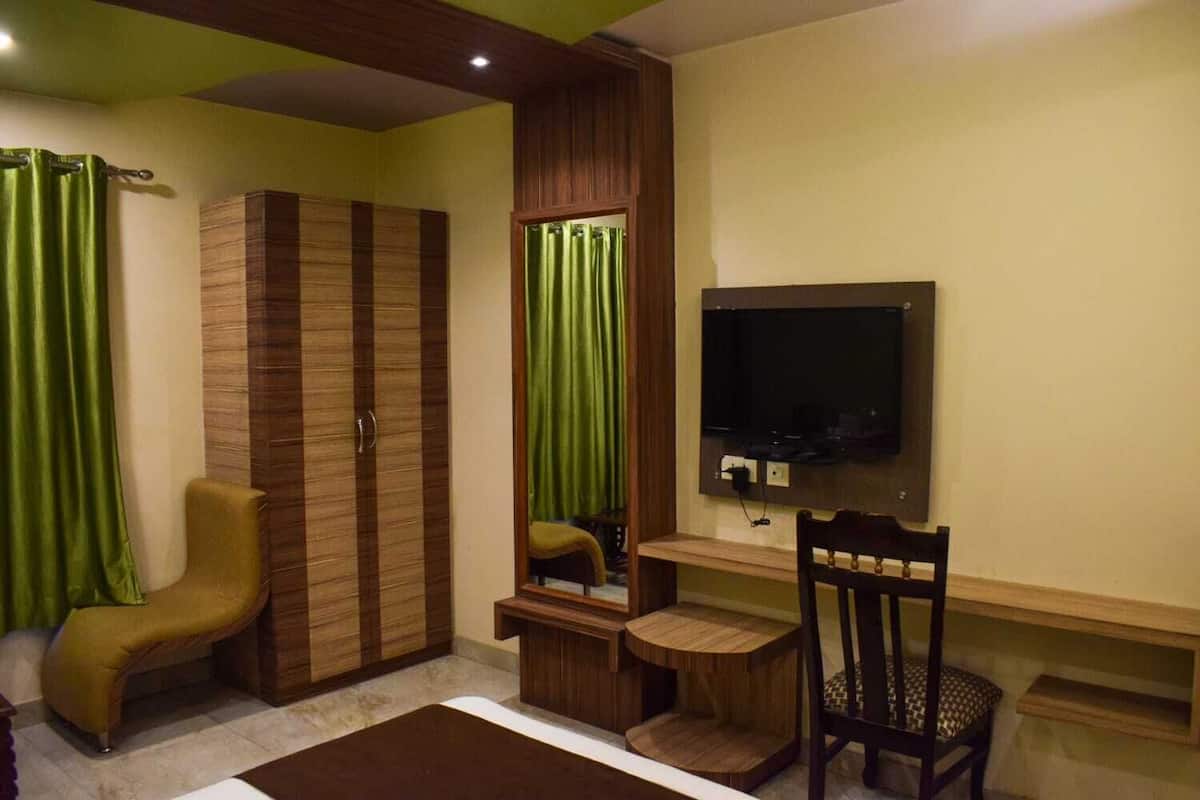 Ein Schlafzimmer mit Kleiderschrank, Bett, Schreibtisch, Sessel und Fernseher.