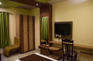 A bedroom with a wardrobe, a bed, a desk, a chair, and a television.