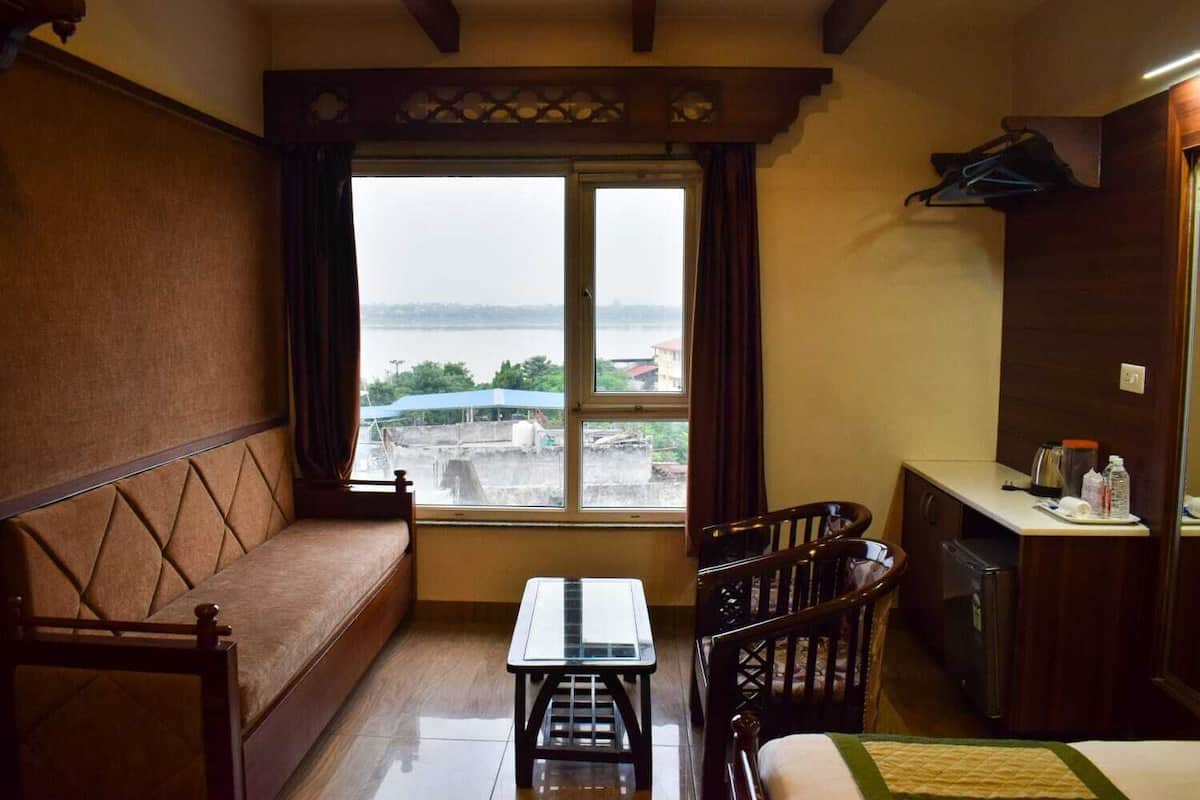 Ein kleiner, gemütlicher Raum mit einer Couch, einem Esstisch und Blick auf ein Gewässer durch ein großes Fenster.