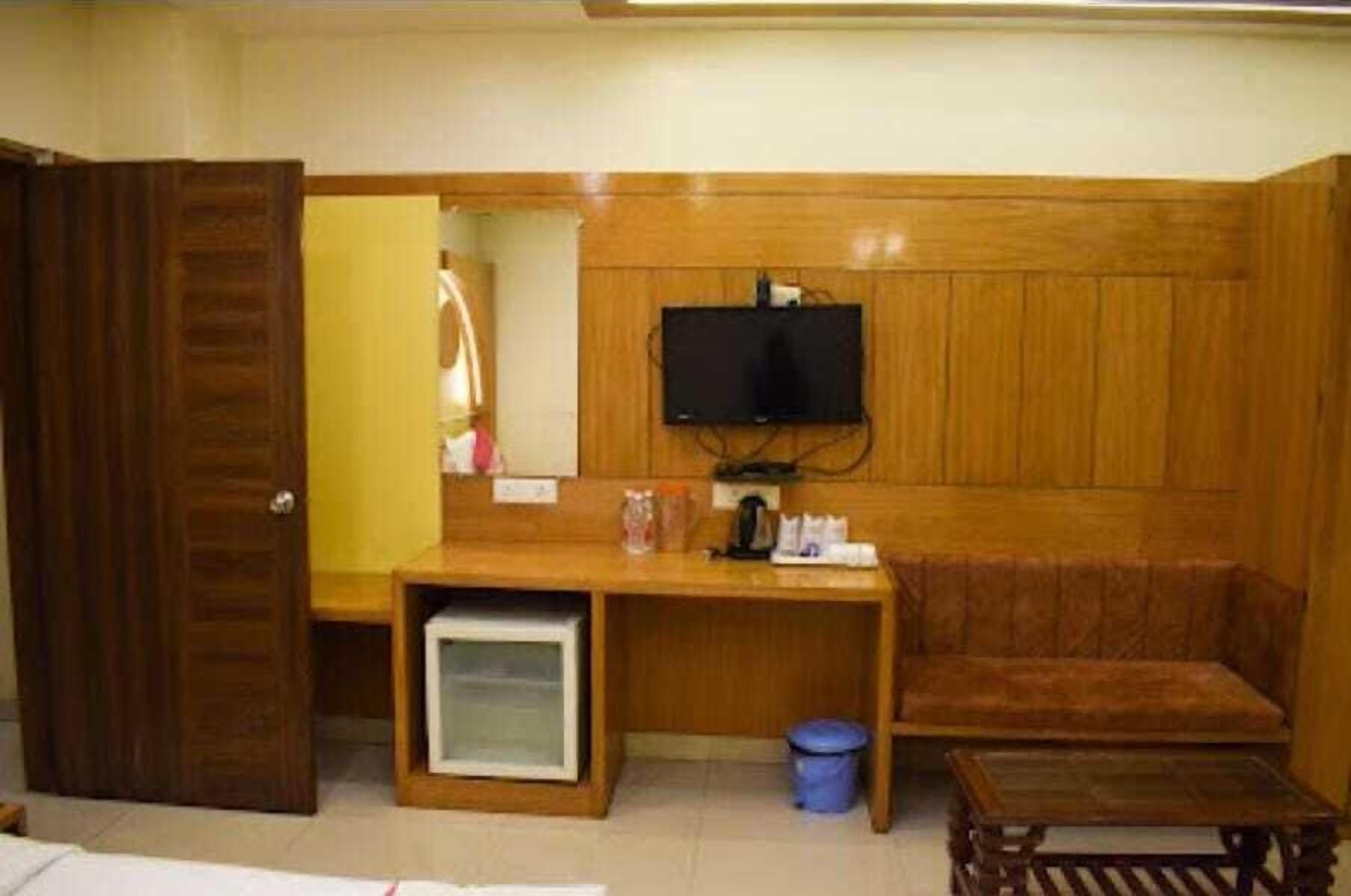 Habitació amb escriptori de fusta, televisió penjada a la paret, sofà i taula petita.