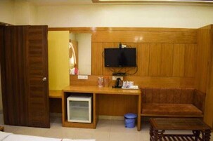 Una habitación con un escritorio de madera, un televisor montado en la pared, un sofá y una mesita.