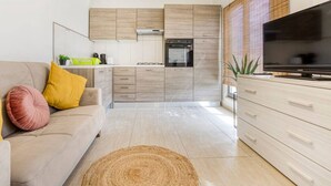 Une cuisine moderne avec des meubles en bois, un four encastré et un téléviseur posé sur un meuble.