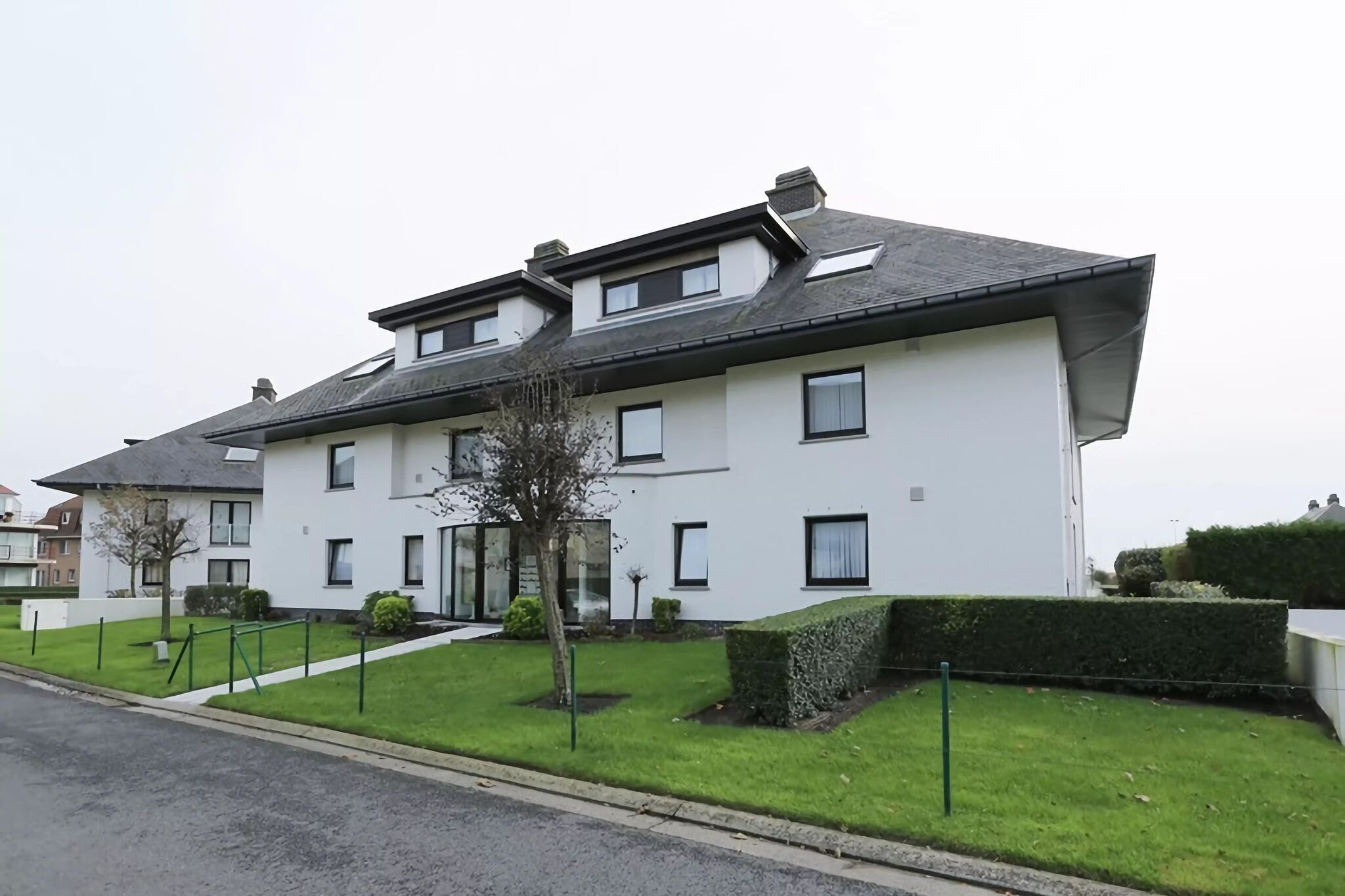 A two-story residential building with a flat roof, multiple windows, and a well-maintained lawn.