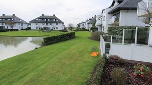 Un quartier résidentiel avec des maisons modernes, une pelouse bien entretenue et un petit étang.