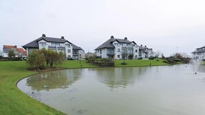 Un quartier résidentiel avec des maisons modernes, un étang et une fontaine.