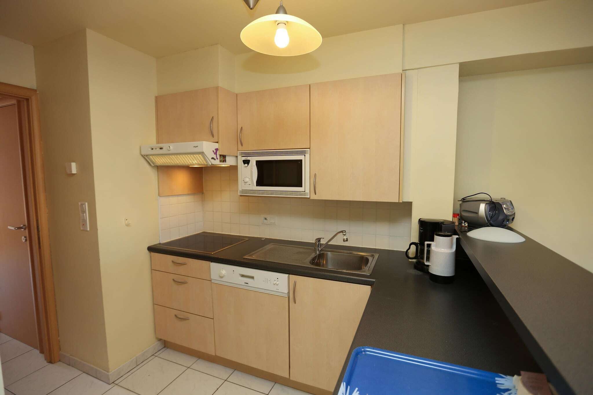 A compact kitchen with wooden cabinets, a microwave, a sink, and a coffee maker.