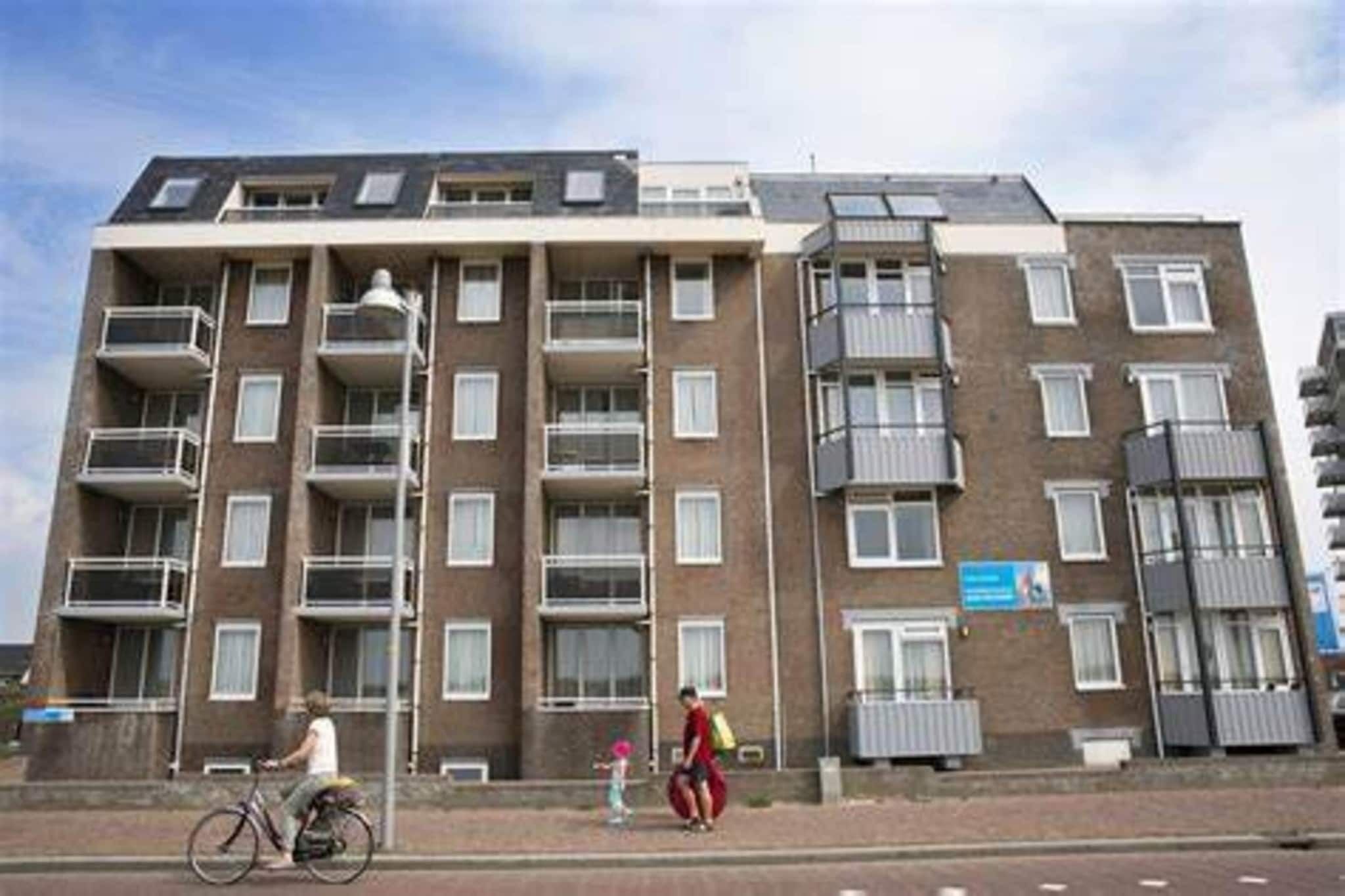 A multi-story residential building with balconies, a brick facade, and a flat roof.