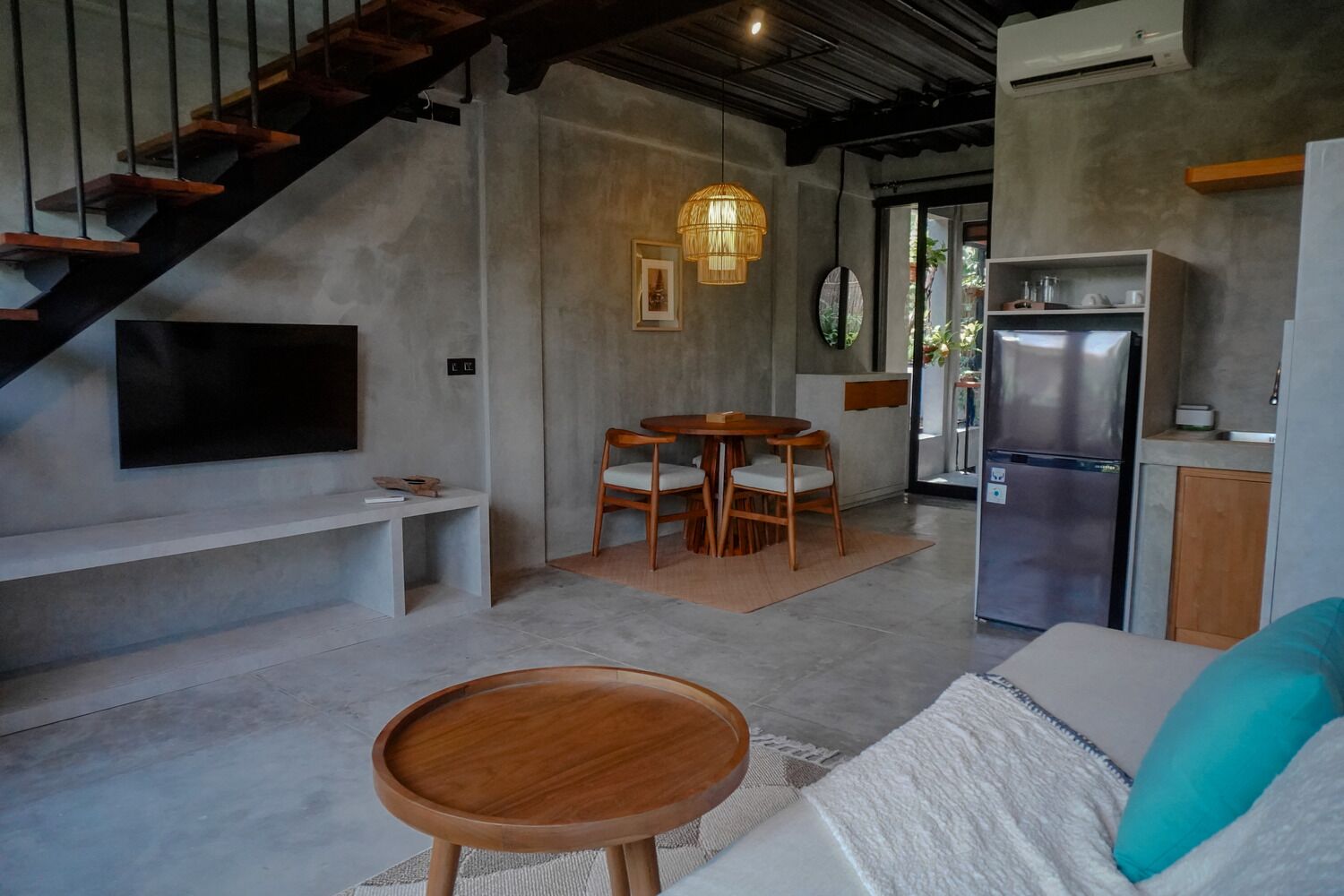 A modern kitchen with a built-in refrigerator, a dining area with wooden chairs, and a staircase leading to an upper level.