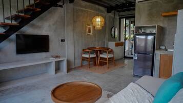 A modern kitchen with a built-in refrigerator, a dining area with wooden chairs, and a staircase leading to an upper level.