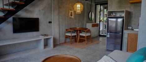 Una cocina moderna con refrigerador empotrado, un comedor con sillas de madera y una escalera que sube a un nivel superior.