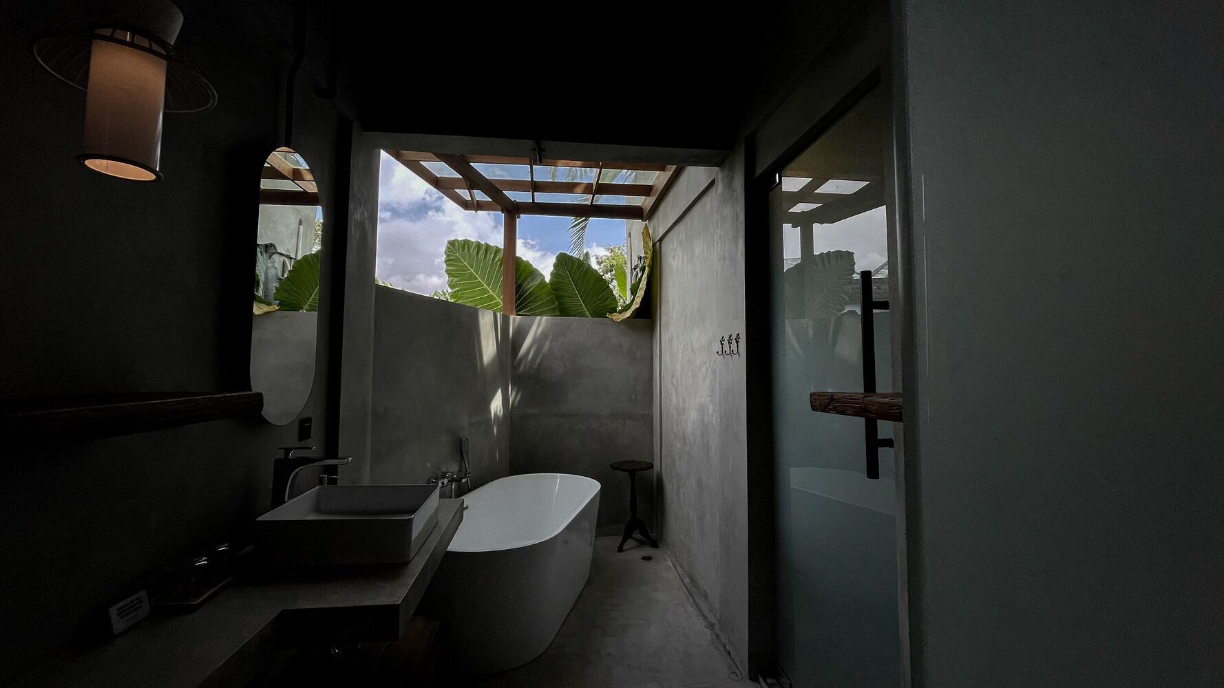 A compact bathroom with a freestanding bathtub, a sink, and a small stool.