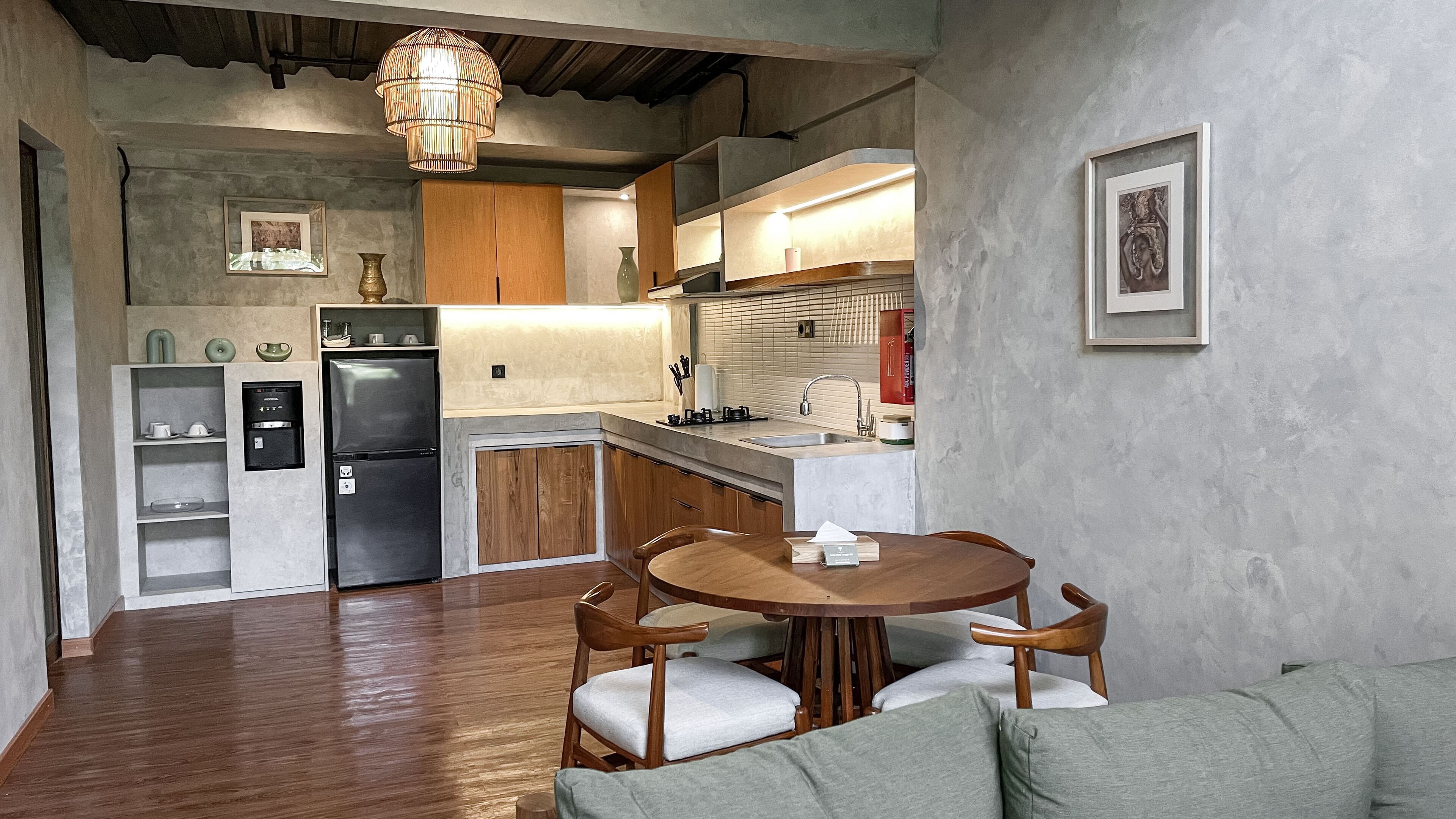 A compact kitchen with wooden cabinets, a built-in refrigerator, and a dining area with a round table and chairs.
