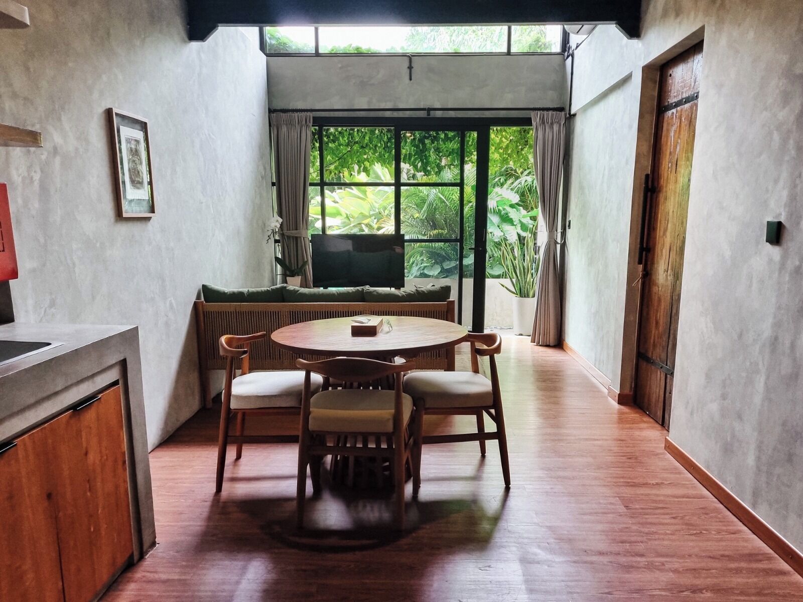Un comedor acogedor con una mesa redonda de madera y cuatro sillas, un sofá y un televisor.