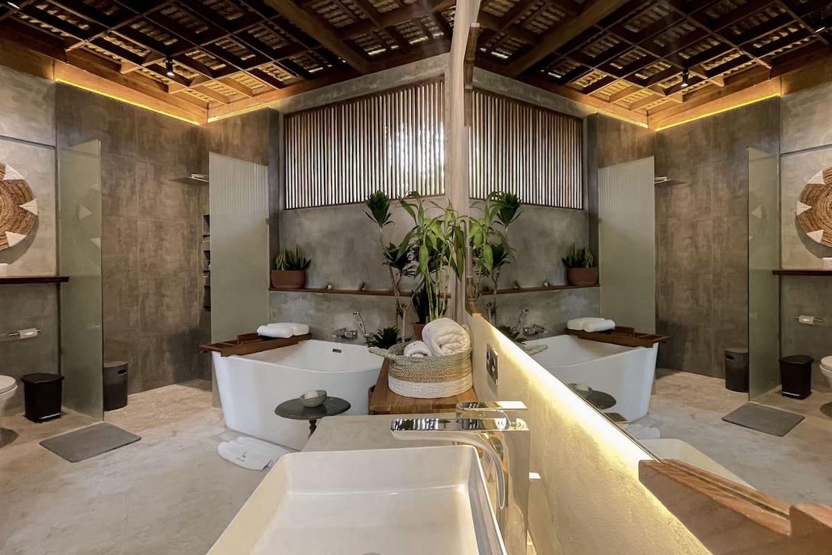 A modern bathroom with a central bathtub, two separate sinks, and a large mirror.