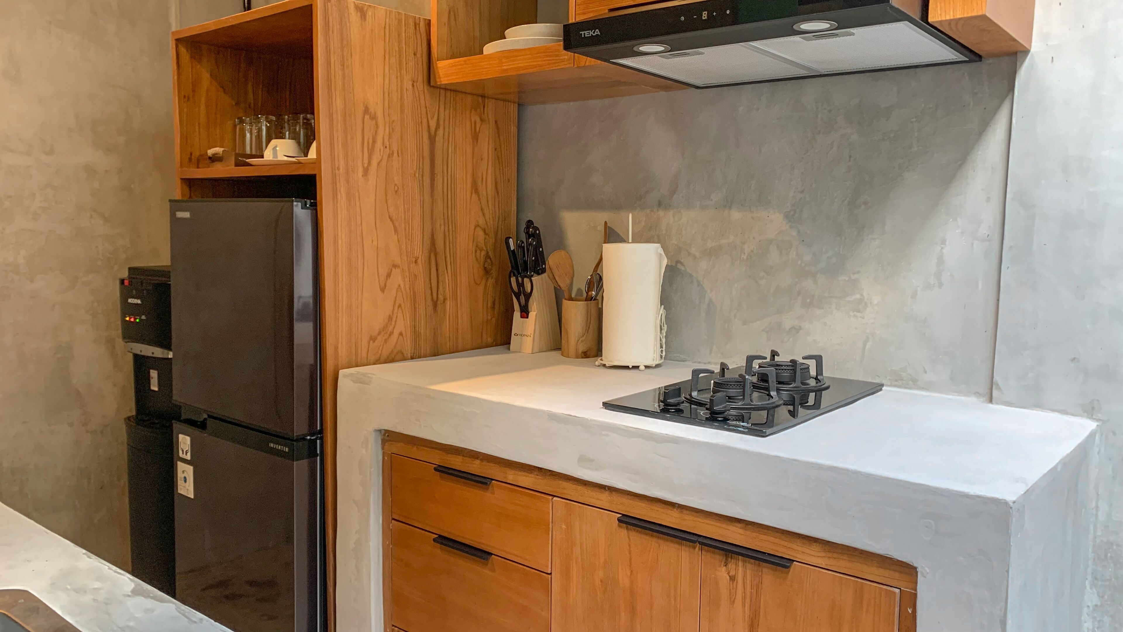 A compact kitchen with a black refrigerator, a built-in stove, wooden cabinets, and a countertop.