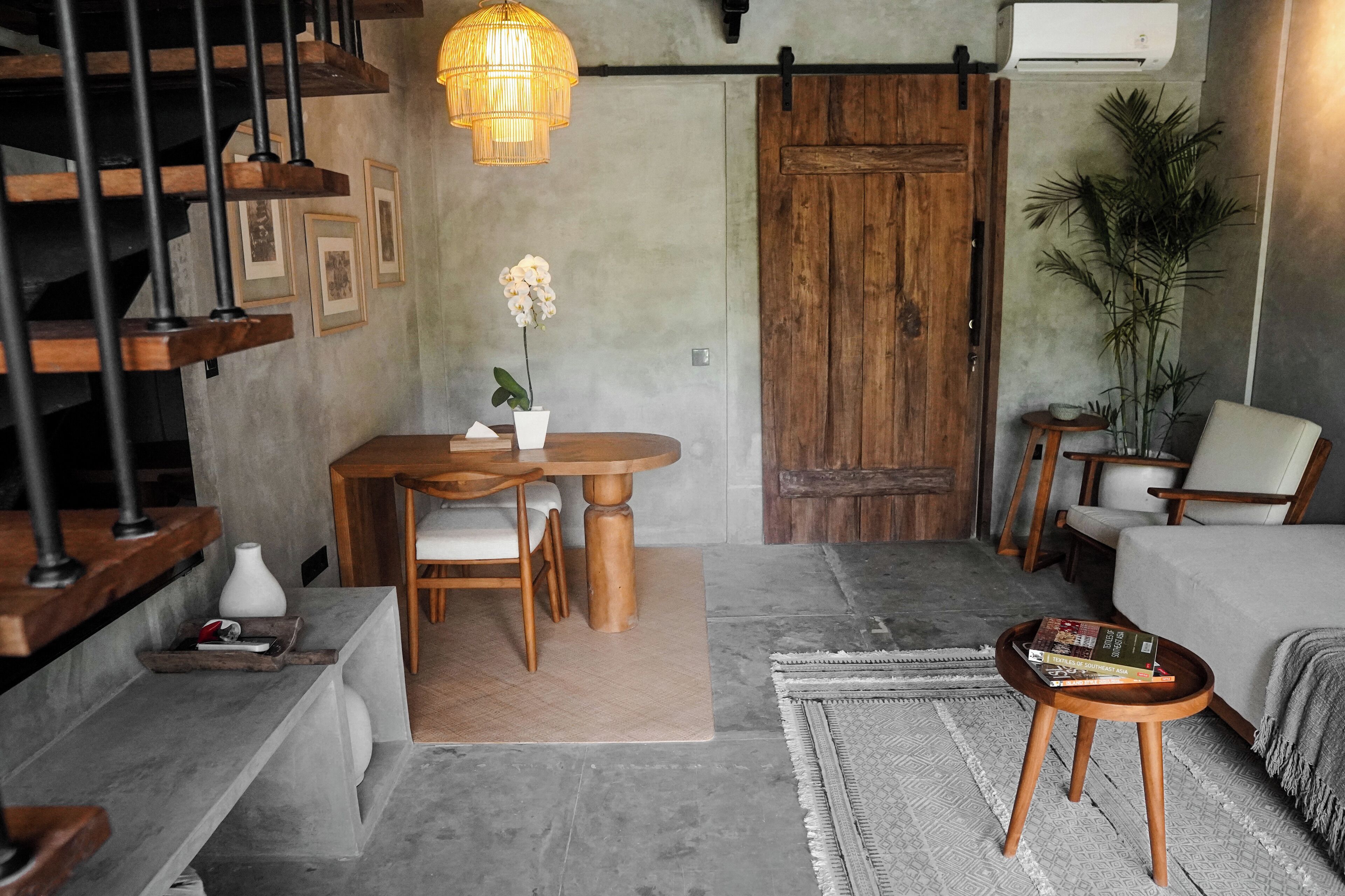 Una sala de estar moderna con comedor, una escalera y una puerta grande de madera.
