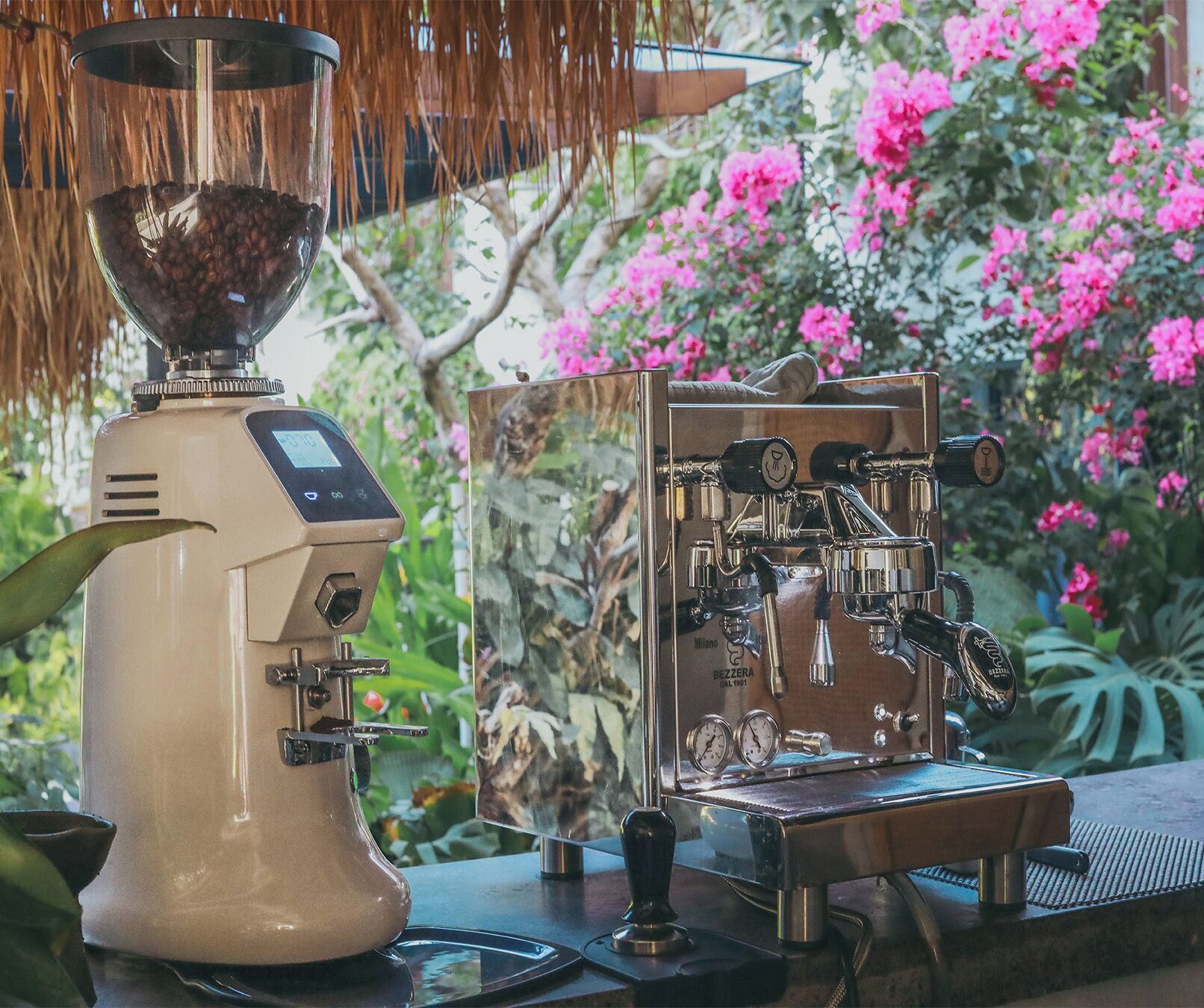 A coffee machine with a digital display and a grinder, placed outdoors with a garden view.