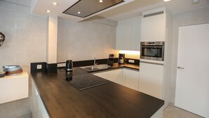 Eine moderne Küche mit dunkler Arbeitsplatte, weißen Schränken, einem eingebauten Ofen und einer Kaffeemaschine.