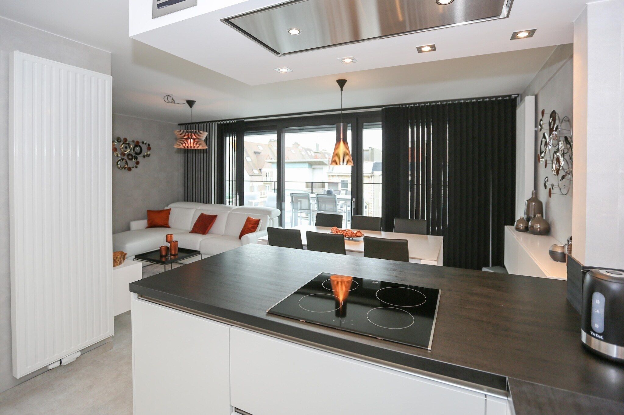 A modern kitchen with a central island, dining area, and a living space with a sofa and coffee table.