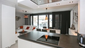 Eine moderne Küche mit Kochinsel, Essbereich und Wohnbereich mit Sofa und Couchtisch.