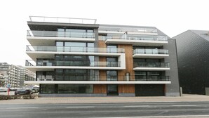 Ein mehrgeschossiges Gebäude mit modernem Design, mit Balkonen und großen Fenstern.