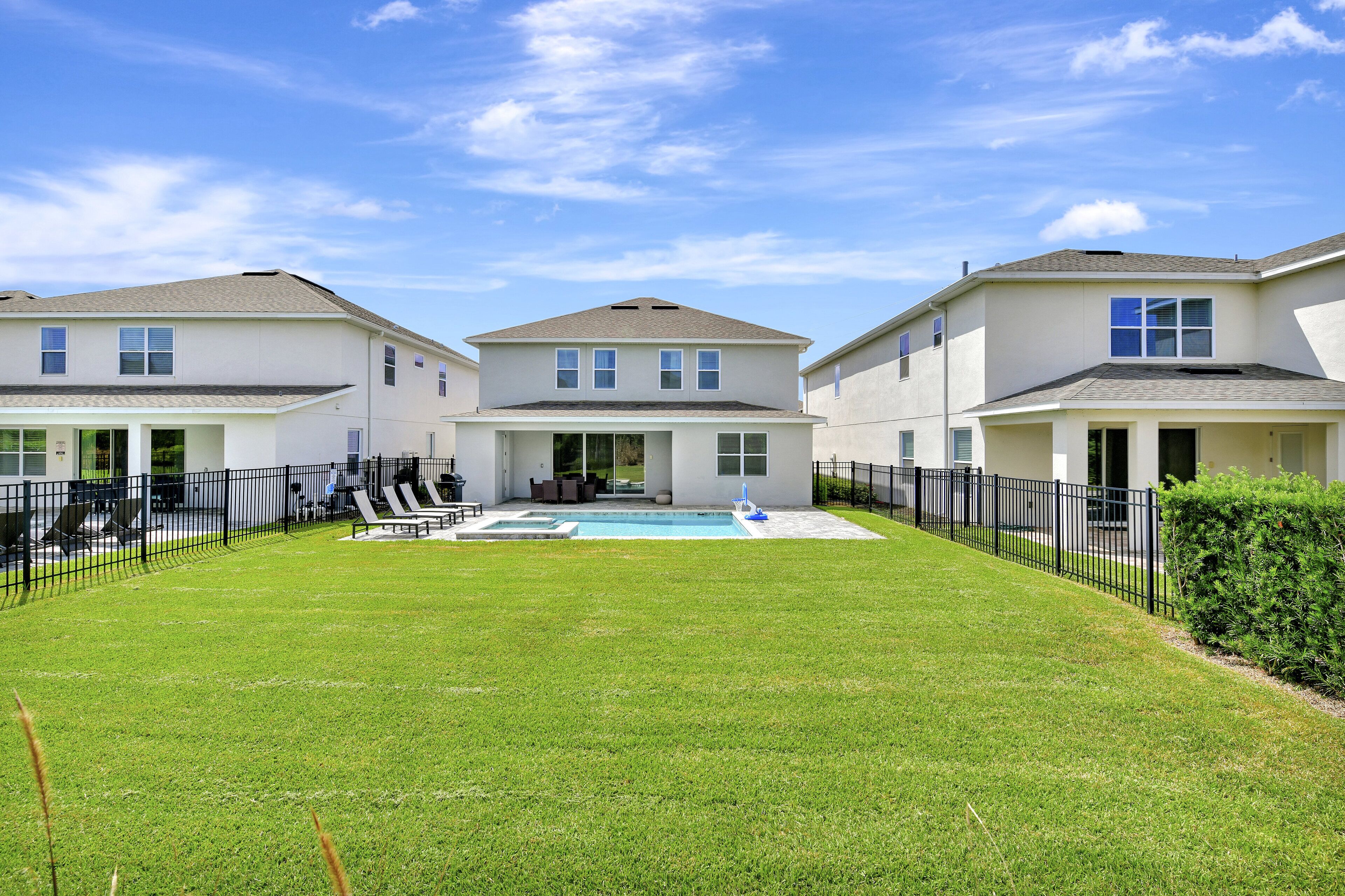 Una propiedad residencial con piscina, patio cubierto y patio trasero cercado.