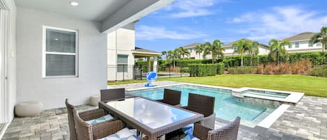 An outdoor patio with a pool, wicker furniture, and a view of a residential area.