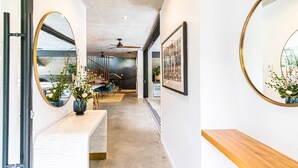 A modern interior with a hallway leading to a dining area, featuring a wooden bench, a mirror, and a ceiling fan.