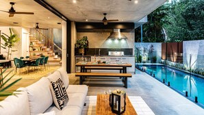 A modern interior with a dining area, kitchen, and a poolside view.