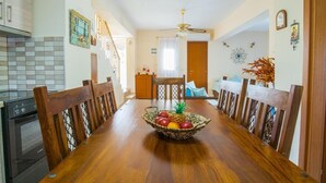 Een eetruimte met een houten tafel, stoelen en een mand met fruit.