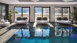 A modern indoor pool area with three seating areas and large windows. - Hotel GRACE LA MARGNA ST MORITZ (St. Moritz)