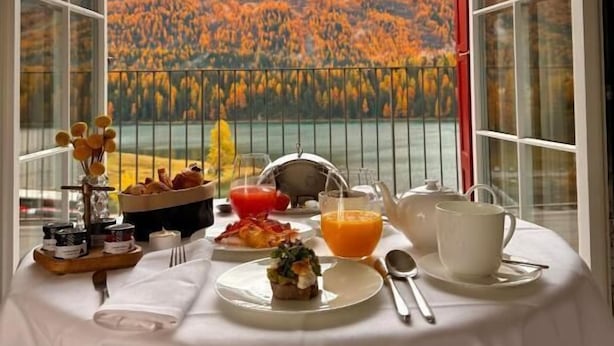 A dining table with a meal set and a scenic mountain view through large windows. - Hotel GRACE LA MARGNA ST MORITZ (St. Moritz)