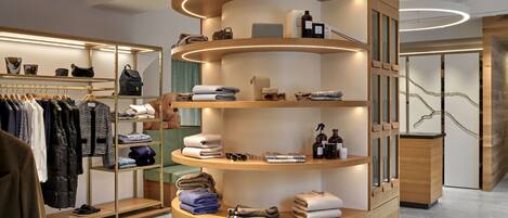 Un présentoir moderne, de forme circulaire et en bois, doté d’étagères où sont rangées des serviettes pliées, des articles de toilette et quelques accessoires.