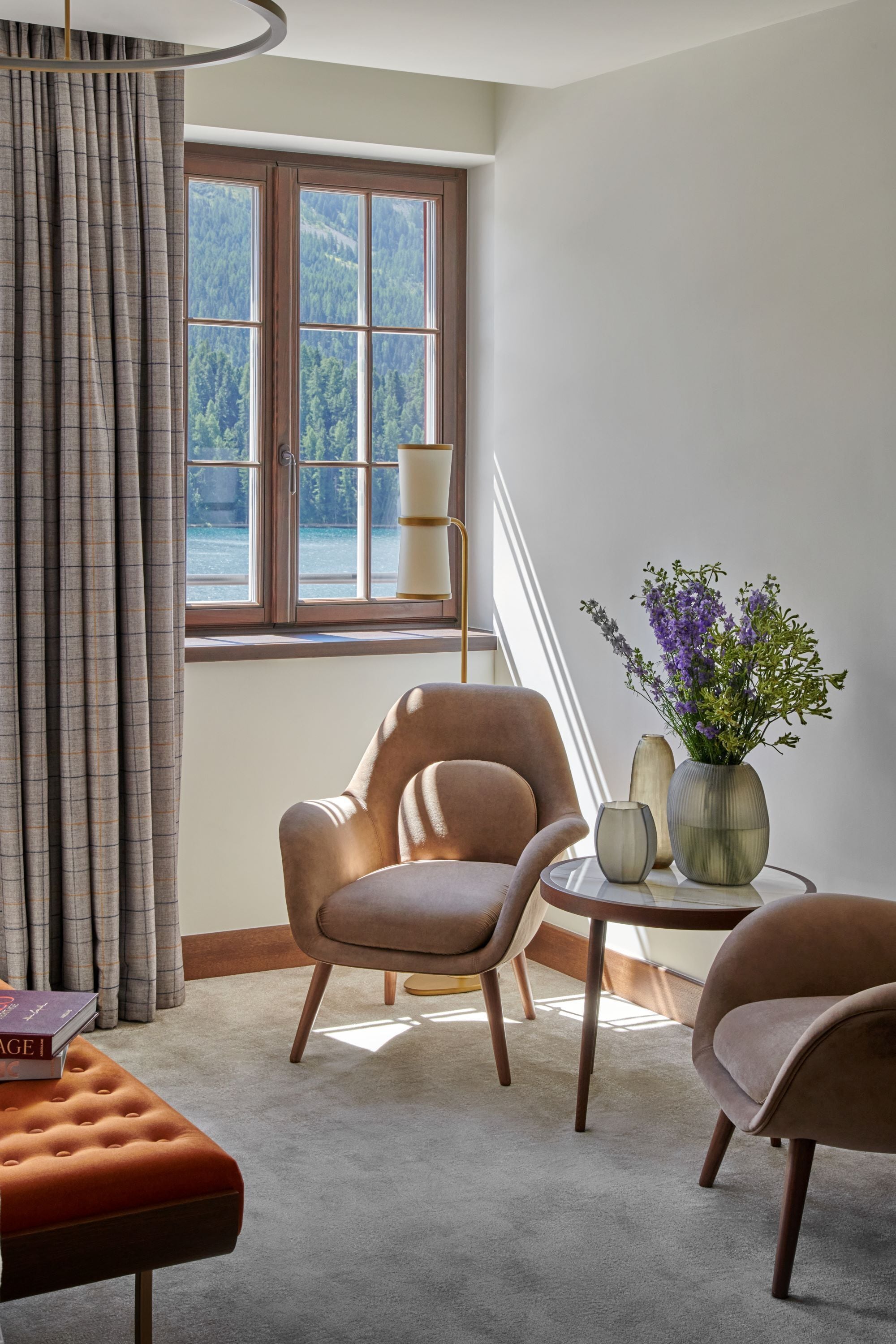 Ein modernes Wohnzimmer mit großem Fenster, einer Couch, einem kleinen runden Tisch und einer Vase mit Blumen.