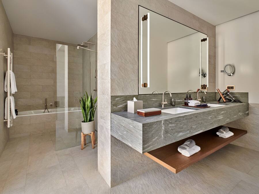 A modern bathroom with a large mirror, dual sinks, and a shower area.