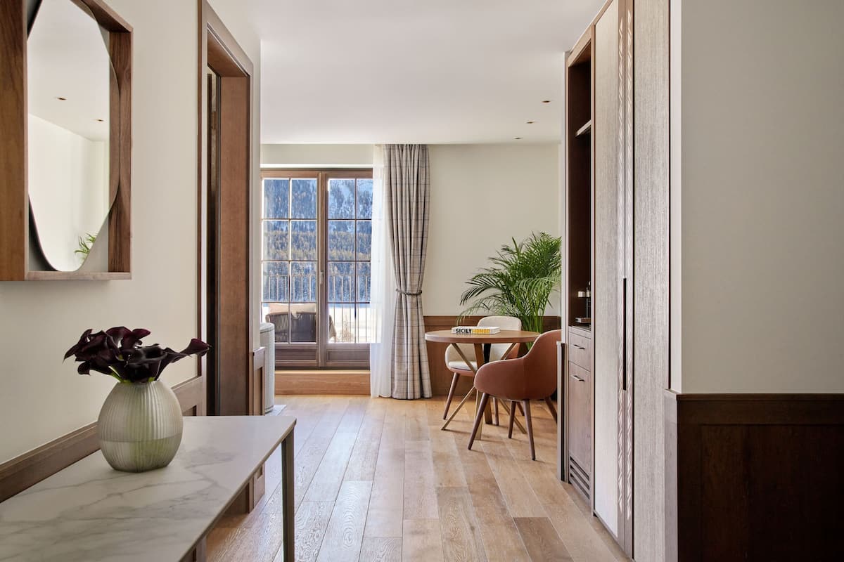 A hallway with a marble bench, a dining area with a table and chairs, and a large window with curtains.