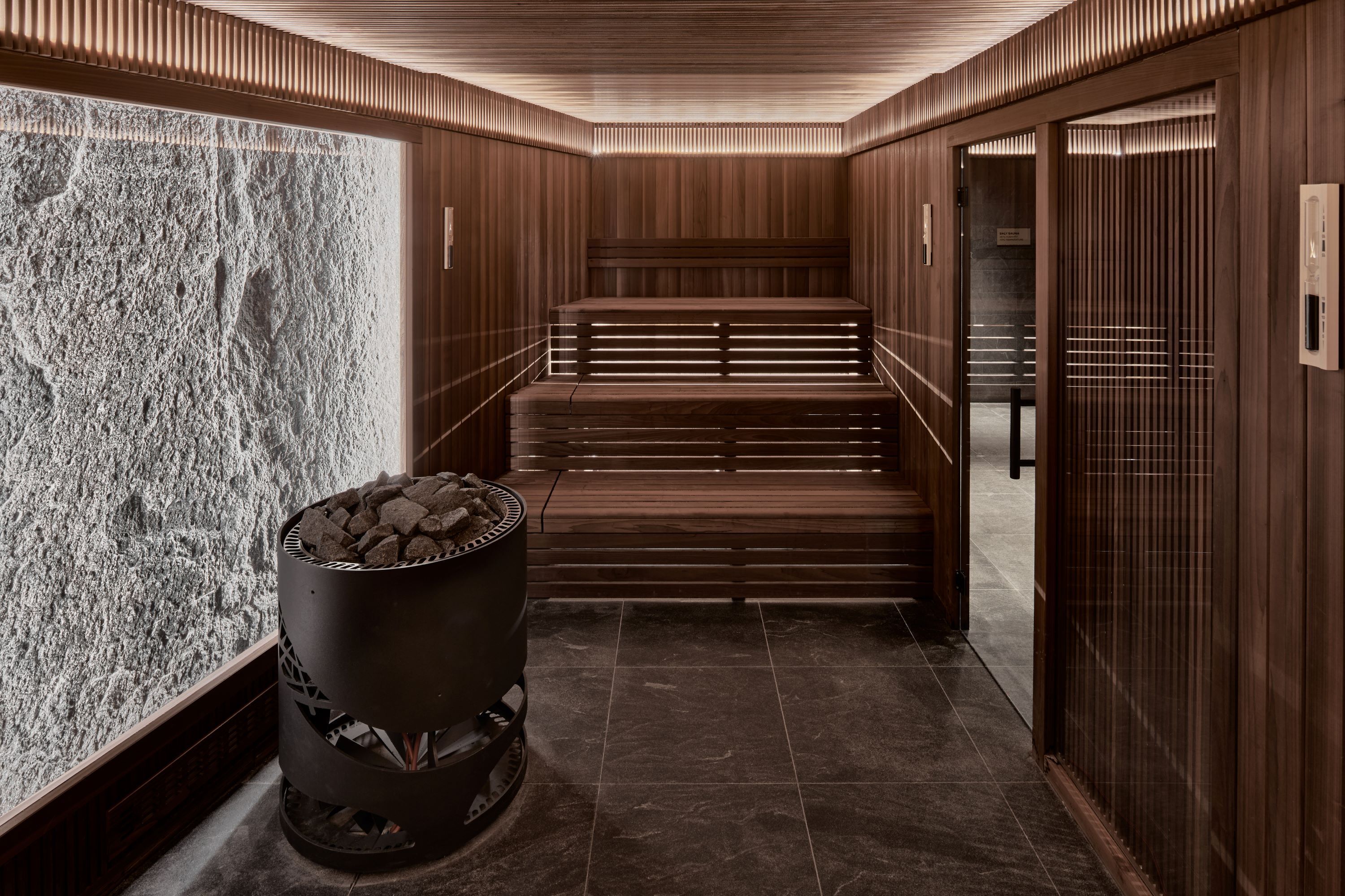 A modern interior with wooden paneling, a stone wall, and a fireplace with logs.