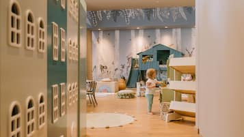 Children can play and explore in this whimsical playroom with a colorful playhouse, arched windows, and a nature-themed mural.
